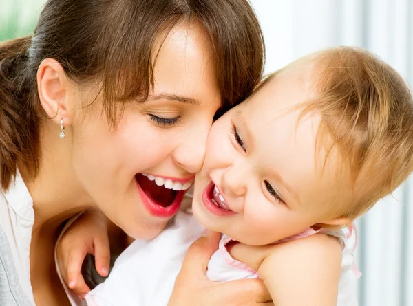 Gelukkig lachend moeder en baby zoenen en knuffelen thuis — Stockfoto