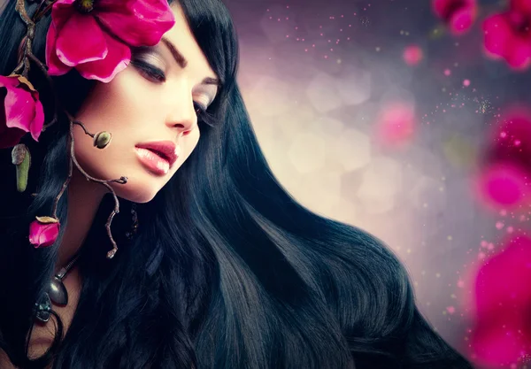 Belleza morena modelo chica con grandes flores moradas en su pelo — Foto de Stock