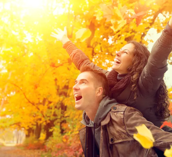 Casal feliz em Autumn Park. Queda. Família se divertindo ao ar livre — Fotografia de Stock