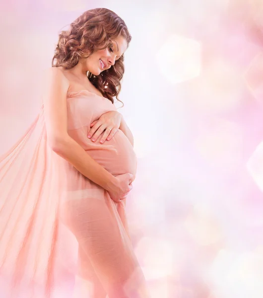 Schönheit schwangere Frau in blasendem rosa Chiffonschal — Stockfoto