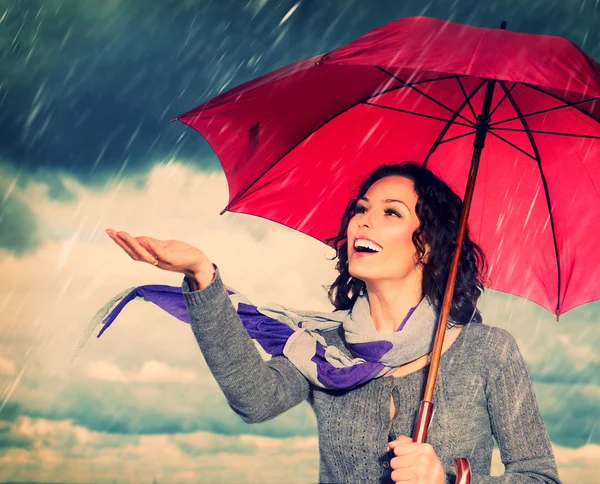 Улыбающаяся женщина с зонтиком на фоне осеннего дождя — стоковое фото