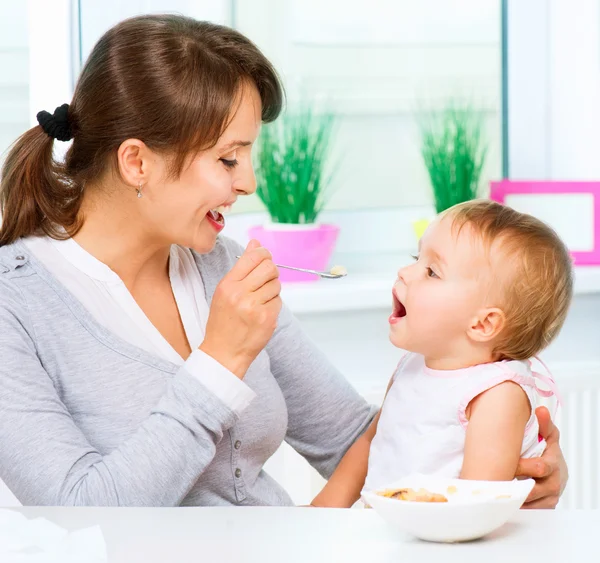 Mãe alimentando seu bebê menina com uma colher — Fotografia de Stock