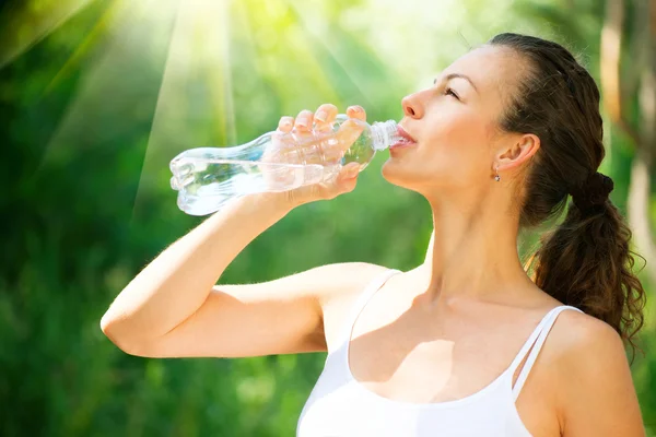 Zdravé a sportovní mladá žena pitnou vodu z láhve — Stock fotografie