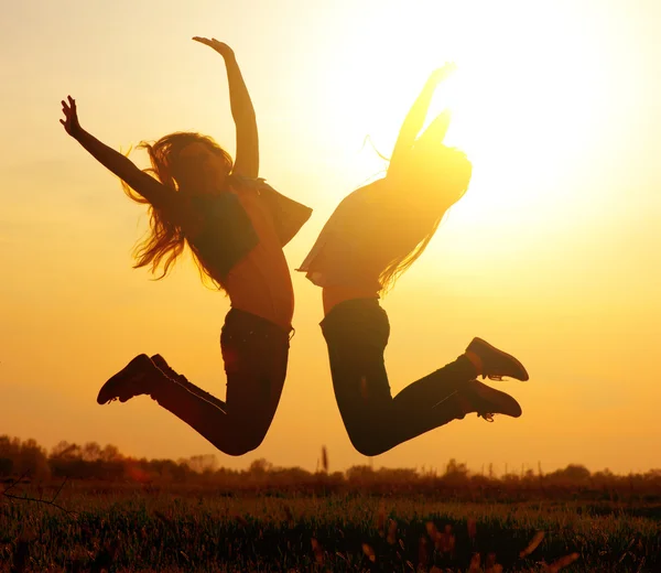 Silhouet van een meisjes springen over zonsondergang Rechtenvrije Stockfoto's