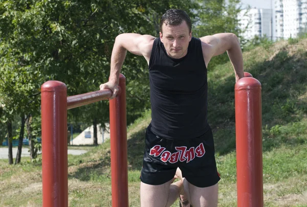 The athlete trains on bars — Stock Photo, Image