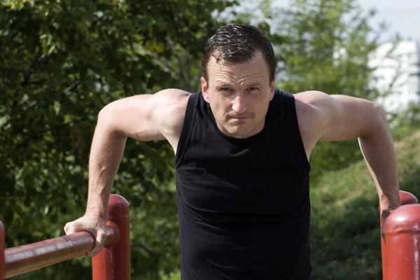 The athlete trains on bars — Stock Photo, Image