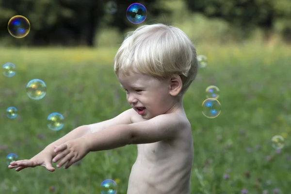 Bebê menino jogar com bolhas de sabão — Fotografia de Stock