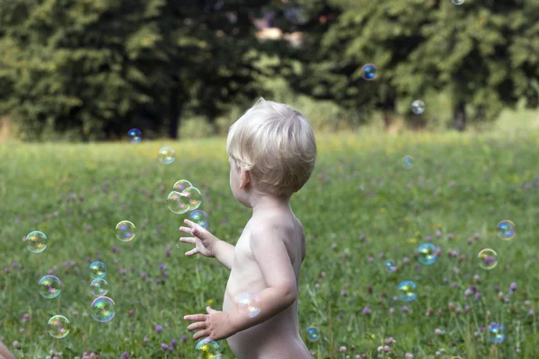 Blond dziecko grać z baniek mydlanych — Zdjęcie stockowe