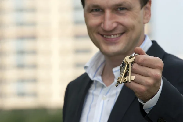 Real estate agent holds out the front door key of a new home