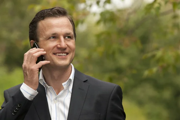 Empresario sonriendo mientras tiene conversación en el teléfono móvil —  Fotos de Stock