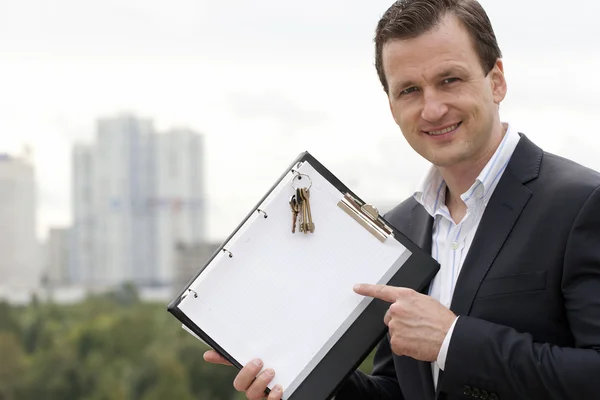 Empresario sosteniendo el signo blanco puro con las llaves de la nueva h — Foto de Stock
