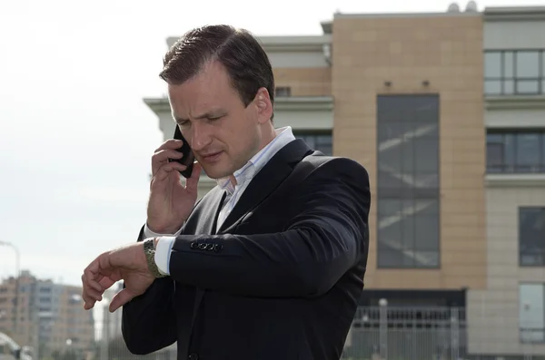 Businessman speaking on the telephone against an office building — Stock Photo, Image