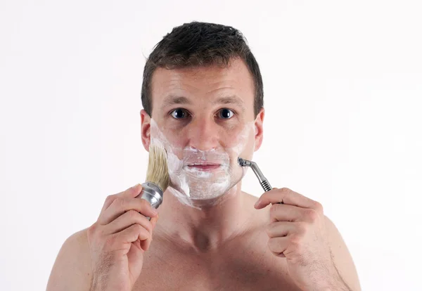 The young man with accessories to shaving. Isolated on a white — Stock Photo, Image