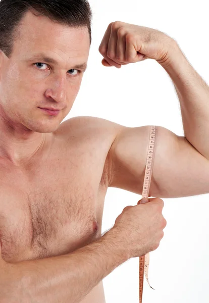 Hombre fuerte midiendo su músculo bíceps. Aislado sobre fondo blanco —  Fotos de Stock