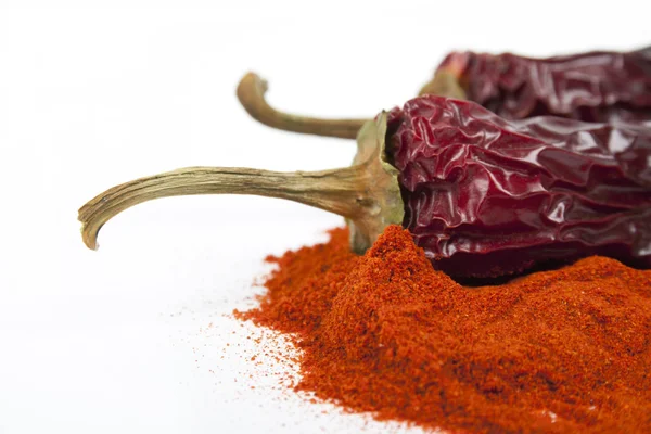 Nahaufnahme von rotem, trockenem Chilipfeffer und einem Häufchen des roten Gewürzes. — Stockfoto