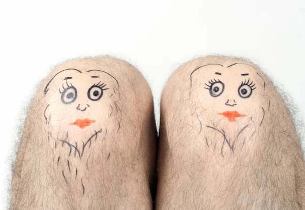 Man's knees with the drawn faces — Stock Photo, Image