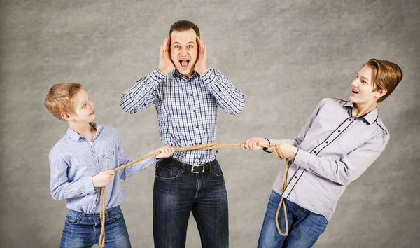 Father and two sons connected by rope Stock Photo