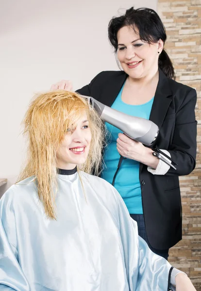 Cabeleireiro seca o cabelo — Fotografia de Stock