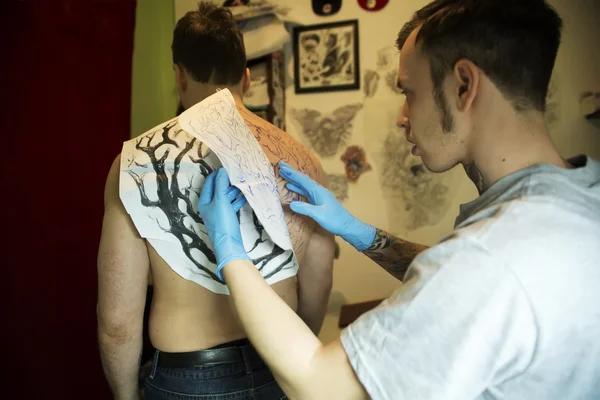 Tattooer gekopieerd de schets op huid — Stockfoto