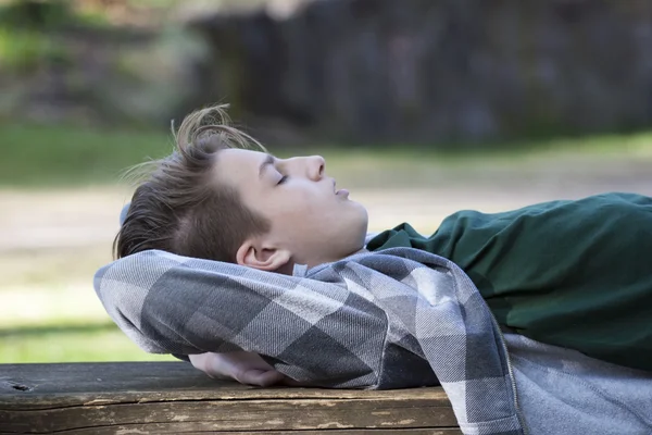 Jongen rusten op een bankje — Stockfoto