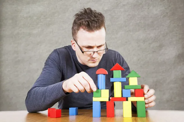 Man builds the house of toy blocks