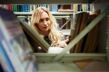 bir kitaplıktaki genç güzel sarışın kız