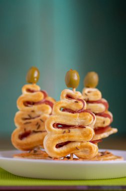 Peynirli, jambonlu ve yeşil zeytinli tuzlu pasta fırını, beyaz tabakta Noel ağacı şekilli bir grup