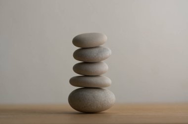 Beyaz zemin üzerinde taş cairn, beş taş kule, basit denge taşları, sadelik ahenk ve denge, kaya zen heykel kulesi