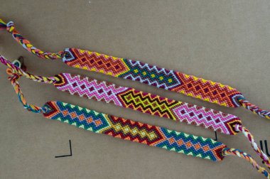 El yapımı, renkli, doğal, dokunmuş arkadaşlık bilezikleri karton kahverengi arka plan, parlak renkler.