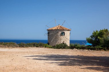 Windmill, Cape Skinari, Zakynthos - 27 Eylül 2021: Kayanın yukarısındaki güzel geleneksel Yunan yel değirmeni