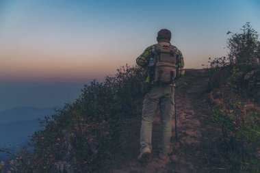 Sırt çantaları dağın tepesinde rahatlar ve güneşin tadını çıkarırlar.