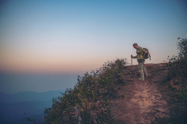 Sırt çantaları dağın tepesinde rahatlar ve güneşin tadını çıkarırlar.