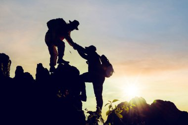 Siluet tırmanış arkadaşları gün doğumunda dağa tırmanırken birbirlerine yardım ederler. Doğru yaşam tarzı fikri olarak.