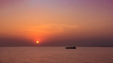 Güzel gün batımında ve batımında açık okyanusta bir gemi.