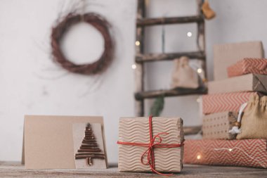 Yeni yıl kompozisyonunun arka planında kırmızı iplik ve el yapımı kartla el yapımı kağıda sarılmış Noel hediyesi. Sürdürülebilir, plastiksiz yaşam tarzı ve sıfır atık. Yüksek kalite fotoğraf