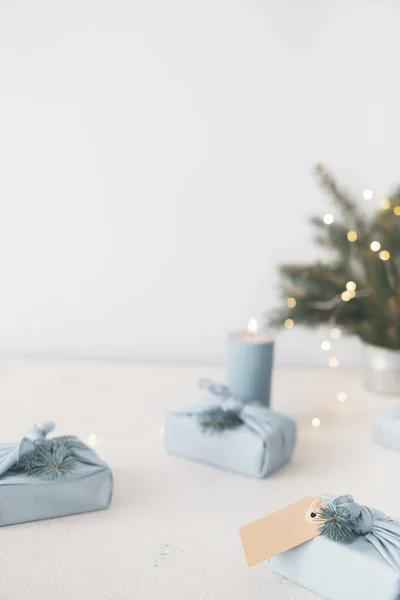 エコフレンドリーな再利用可能なファブリックパッケージでクリスマスギフト 灰色の背景にモミの枝やタグを飾る 和風風呂敷 最上階だ テキスト用の場所 高品質の写真 — ストック写真