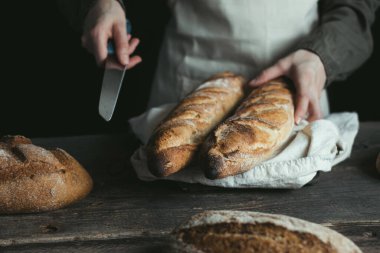 Rye bread. Female hands are going to cut a loaf. Bread without yeast. Concept of healthy food and traditional baking. High quality photo