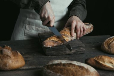 Female hands are cutting rye loaf. Bread without yeast. Concept of healthy food and traditional baking. High quality photo