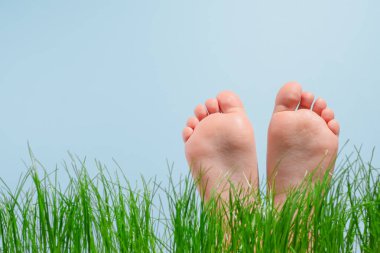 Çocukların çıplak ayakları yeşil çimlerde, mavi arka planda izole edilmiş. Bahar. Çıplak ayaklar. Yalınayak. Sağlıklı ayak. Yüksek kalite fotoğraf