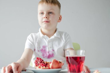 Çocuk bir nar açıyor ve elbiselerini kirletiyor. Günlük hayatın kirli lekeleri. Yüksek kalite fotoğraf