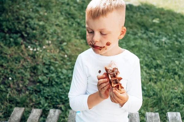 Ребенок ест бельгийские вафли с шоколадной начинкой. Вид сверху. повседневной жизни грязные пятна для мытья и чистой концепции — стоковое фото