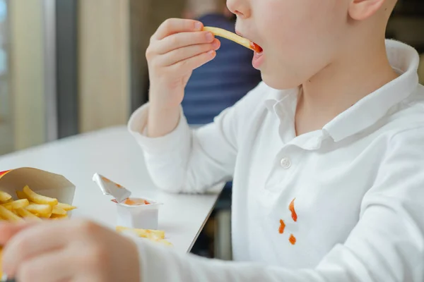 백인 애들 옷에 케첩 얼룩을 덮어. 패스트푸드 점에서 감자튀김 감자칩 과 토마토 소스를 먹는 소년. 어린이들은 건강에 좋지 않은 지방 음식을 먹는다. — 스톡 사진