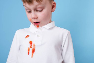 Çocuk, domates sosundan dökülen kirli bir leke ve kıyafetlere konan spagetti yemeğine şaşırdı. Günlük yaşam lekesi konsepti. Yüksek kalite fotoğraf
