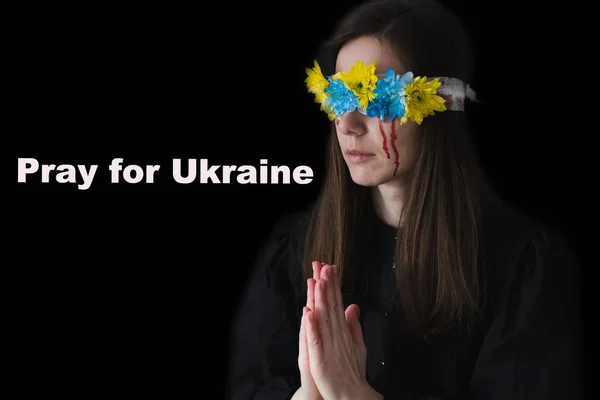 Szomorú nő csukott szemmel kék-sárga virágokkal és könnyekkel az arcán, hogy békéért imádkozzon. A háború Ukrajnában — Stock Fotó