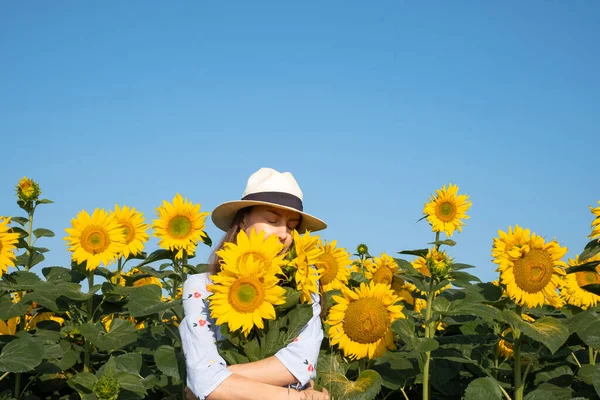 Mavi gökyüzünün arka planında bir buket ayçiçeği buketine sarılan mutlu kadın. Özgürlük kavramı Ukrayna