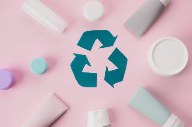 Plastik geri dönüşüm işareti. Pembe arka planda kullanılmış kozmetik tüpleri ve güzellik ürünleri. Gezegeni kurtar. Düz yat. Üst Manzara. Yüksek kalite fotoğraf