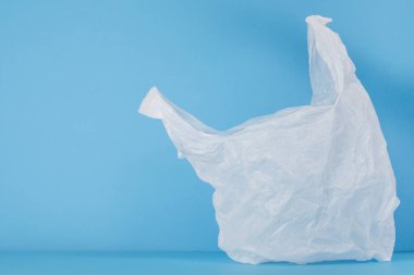 Mavi arka planda tek kullanımlık beyaz plastik torba. Mesajın için yer aç. Plastiksiz konsept. Yüksek kalite fotoğraf