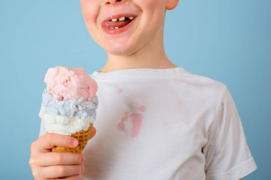 Dondurma yalayan çocuk gözlerini kapattı. Kirli dondurma lekesi beyaz kıyafetlerde. Günlük yaşam lekesi ve temizlik konsepti. Yüksek kalite fotoğraf