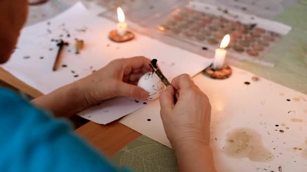 Females hands painting a traditional Ukrainian pysanka. Easter eggs decoration process with wax paint and fire. — Stock Video