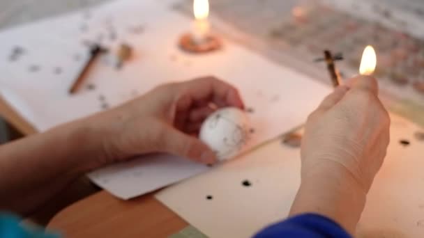 Samičí ruce malují tradiční ukrajinskou pysanku. Velikonoční vejce dekorace proces s voskovou barvou a ohněm. — Stock video